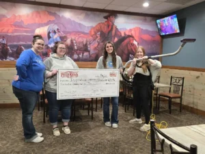 Employees from Inspirations hold a large check